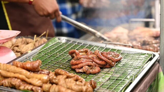 Thai street vendor preparing authentic local snacks at a bustling night market stall in Thailand; chef cooking delicious Asian street food with vibrant night lights and lively atmosphere.