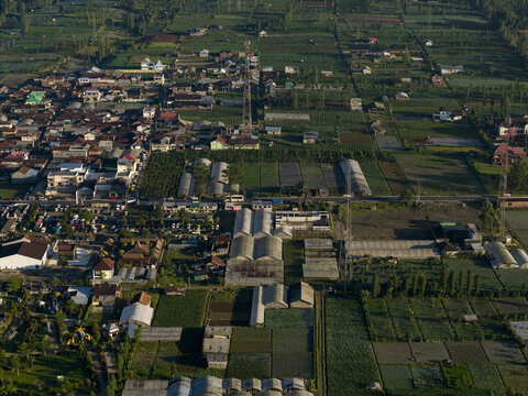Aerial view of the village of Yososari featuring agricultural fields, greenhouses, and residential houses Kecamatan Kertek, Jawa Tengah, Indonesia.