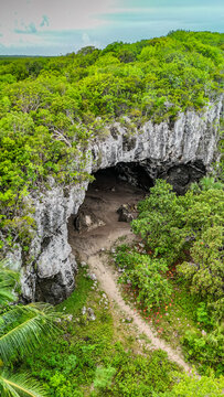 Aerial view of Preacher's Cave surrounded by lush tropical forest and a sandy path in The Bluff Settlement, North Eleuthera, The Bahamas.