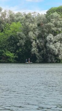 Fishermen on a Small Boat Fishing on a Quiet River Surrounded by Lush Forest