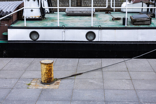 Mooring bollard with rope and docked ship at waterfront