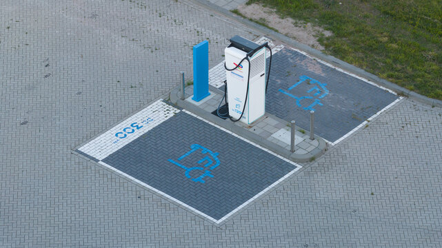 Roosendaal, Netherlands - 25 April 2026: Aerial view of an electric vehicle charging station with two designated parking spots featuring blue icons on a paved surface.