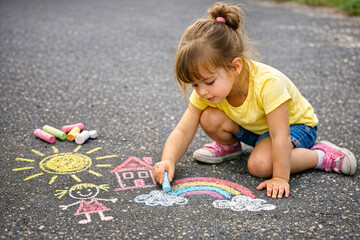 Fototapeta premium Young Girl Drawing Chalk Pictures on Asphalt Road