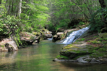Water cascades down a picturesque waterfall where remote rivers join.  Rock ledge in the foreground. © John