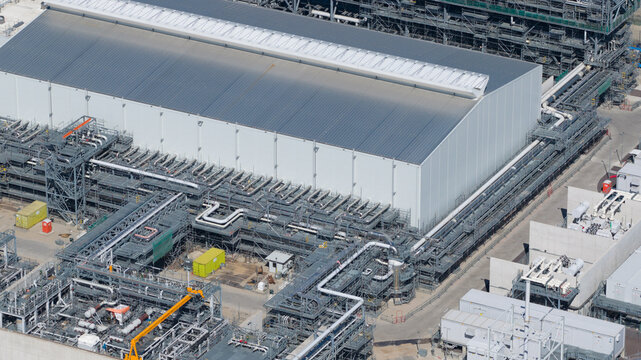 Maasvlakte Rotterdam, Netherlands - 25 April 2026: Aerial view of the Holland Hydrogen I facility featuring a large white industrial building and complex piping infrastructure.