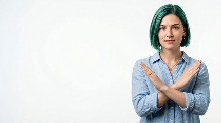 Fototapeta premium A young woman with green hair makes a dismissive gesture with her hand in a photo studio to indicate a firm refusal or self-restraint.