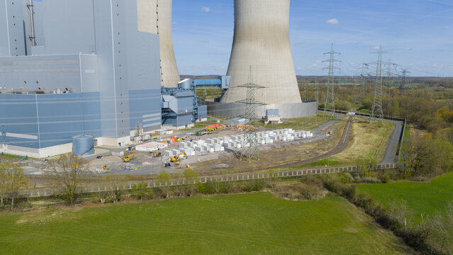 Hamm, Germany - 06 April 2026: Aerial view of the RWE Westfalen power plant featuring massive cooling towers, industrial facilities, and power lines surrounded by green fields.