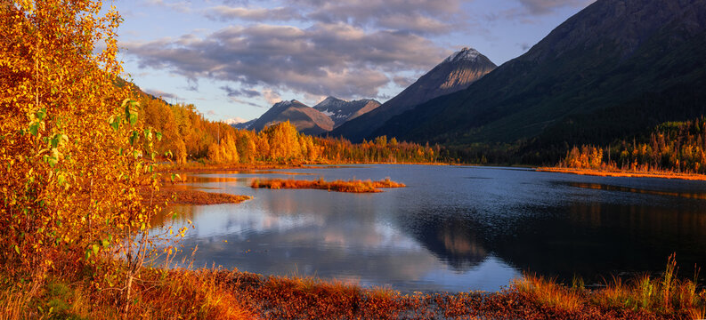 Alaskan wilderness lake reflecting autumn mountains at sunset