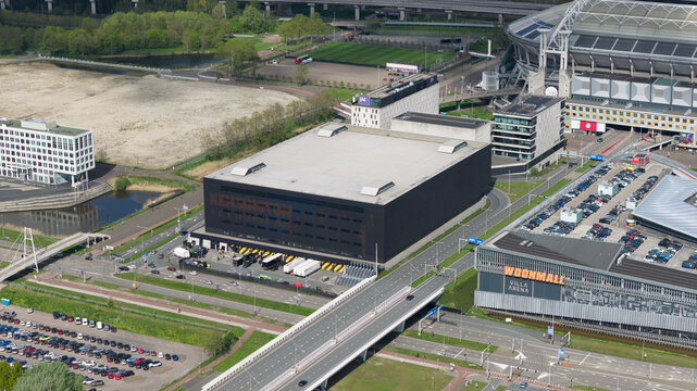 Amsterdam, Netherlands - 19 April 2026: Aerial view of the Ziggo Dome indoor arena and surrounding urban infrastructure including the Johan Cruyff Arena and parking areas.