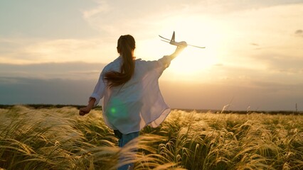 Happy kid girl runs with toy airplane on field in sunset light. Child play toy airplane. Kid aviator dreams of flying becoming pilot. Little girl child wants to become pilot astronaut sky. Slow motion © Victoriia