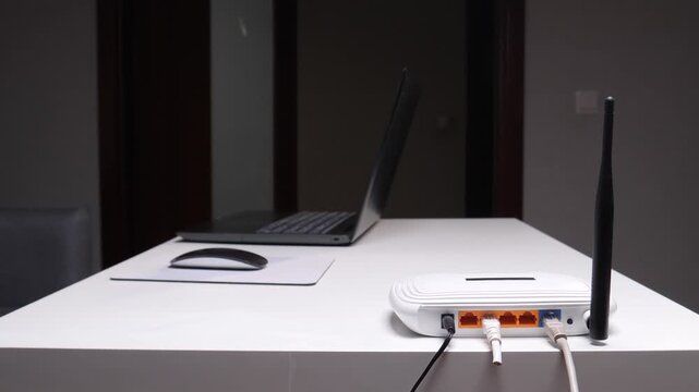 Close up of person using scissors to cut an ethernet cable connected to a wireless router, symbolizing internet disconnection, broken network, loss of communication, and technology failure