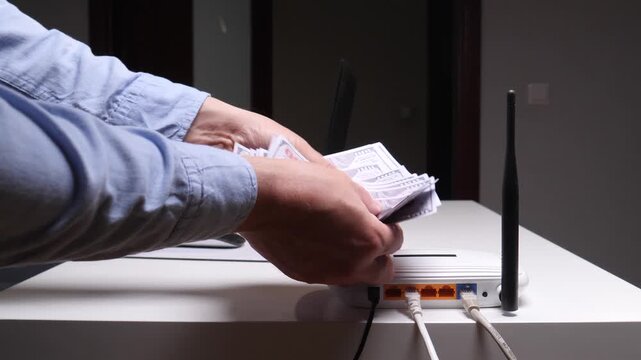 Hands holding dollar banknotes for a payment, counting money on top of a router, representing internet expenses, utility bills, and network service fees