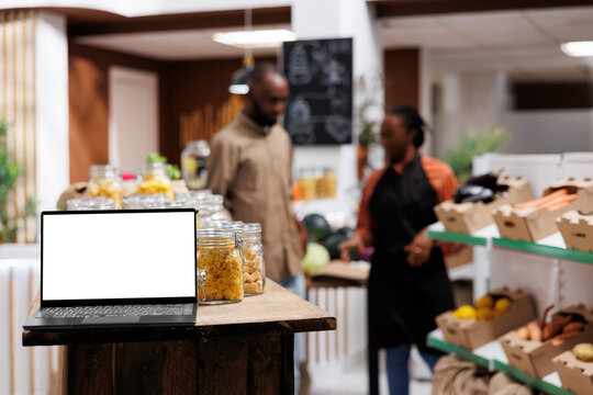 Selective focus on the wireless device displaying an isolated chromakey template in an eco friendly shop. In a modern food store, a minicomputer is showing a blank white screen.