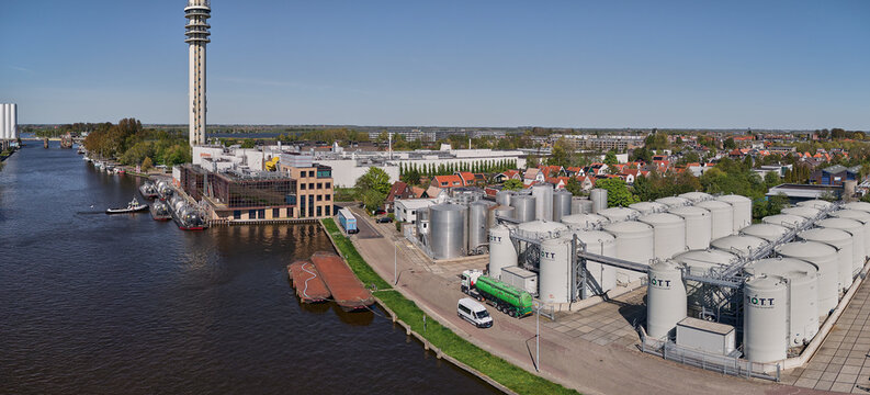 Wormer, Netherlands - 02 June 2026: Aerial view of the Marine Oil Tank Terminal and Cargill cocoa factory along the Zaan river with the KPN telecom tower under a clear blue sky.