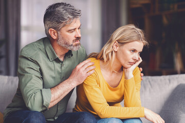 Fototapeta premium Worried Man Comforting Upset Woman During Emotional Discussion At Home Setting. Middle-aged Caucasian Experiencing Relationship Challenges, Seeking Support And Understanding Together