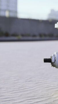 A fire hydrant stands on a sidewalk surrounded by buildings. The ground shows patterns in the surface. It is daytime and the sky is clear.
