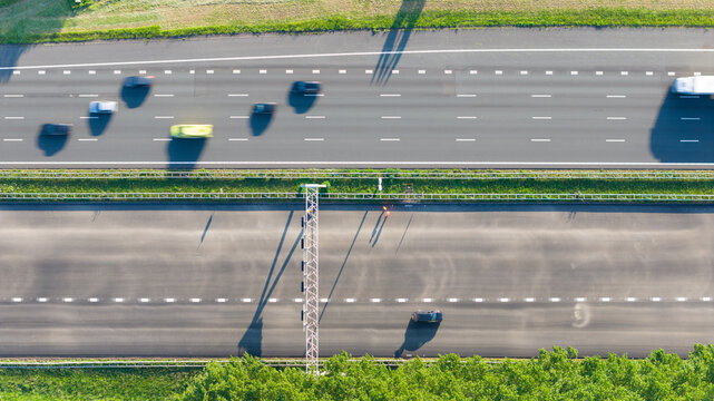 Nieuwegein, Netherlands - 09 May 2026: Aerial view of a multi-lane highway with cars driving past a gantry structure and green verges under bright sunlight.