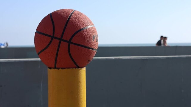 Basketball In Sunlight On Yellow Parking Lot Post