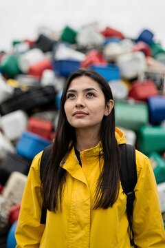Young woman standing before a large plastic waste pile highlighting environmental pollution sustainability challenges and recycling awareness
