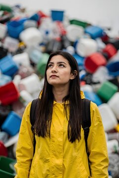 Young woman standing before a large plastic waste pile highlighting environmental pollution sustainability challenges and recycling awareness
