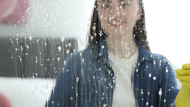 Woman cleaning window with detergent and rag indoors, selective focus