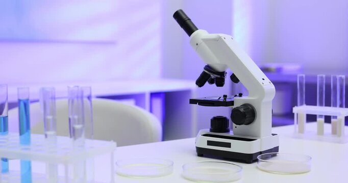 Laboratory testing. Different samples of milk and microscope on white table indoors, camera moving left