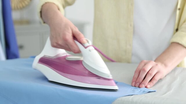 Woman ironing shirt on board at home, closeup