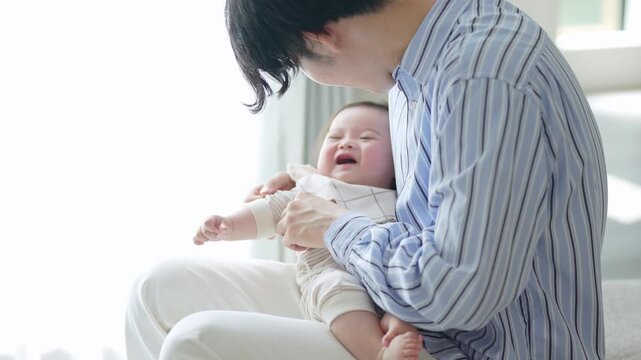 赤ちゃんに服を着せるお父さん