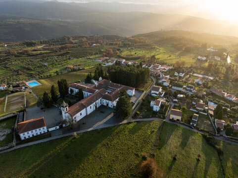 Vila Pouca da Beira, Portugal - 31 December 2023: Aerial view of the Lam Hotel Convento do Desagravo surrounded by green fields and rolling hills under a warm golden sunset light.