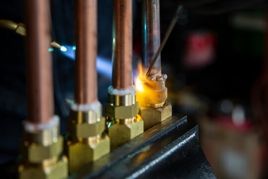 銅管の継手をガストーチの炎でろう付けする配管加工の作業と銀ろうのクローズアップ