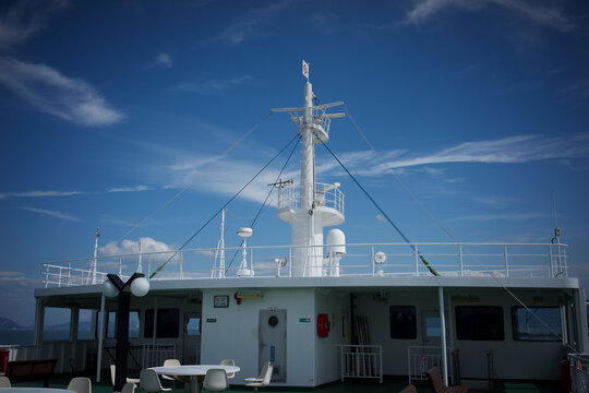 White ferry boat deck and mast sailing under beautiful blue sky with white clouds