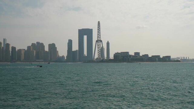 sunny day dubai city palm island famous bay ferris wheel modern hotel exterior water traffic slow motion panorama 4k uae
