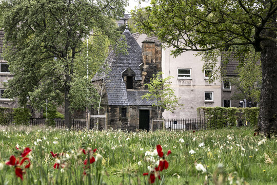 View of Queen Mary's Bath House with a pointed slate roof and spring flowers in a garden in Edinburgh, Scotland, United Kingdom.