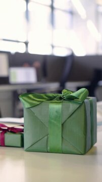 Vertical video: Panning camera centering green gift on desk, showing decor, magenta gift and trees