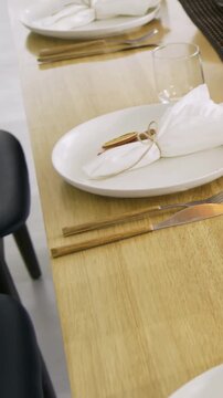 Vertical video: Panning camera revealing dining table in home, preparing meal with salad, napkins