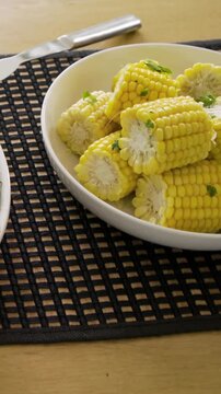 Vertical video: Panning camera showing corn bowl on table to reveal meal, with fork, glass, basket