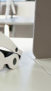 Vertical video: Panning shot showing VR headset side view in office, charts, stand and grey panel