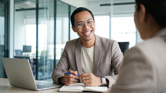 Happy Indonesian professional business man executive hr or bank manager, lawyer or financial advisor having job interview or business conversation consulting client at corporate office meeting.