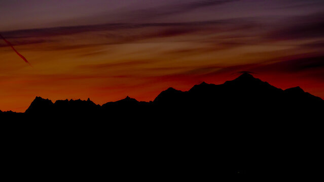 View of the silhouette of the Mont Blanc massif under a dramatic sunset sky with orange and purple clouds in Chamonix, Auvergne-Rhone-Alpes, France.