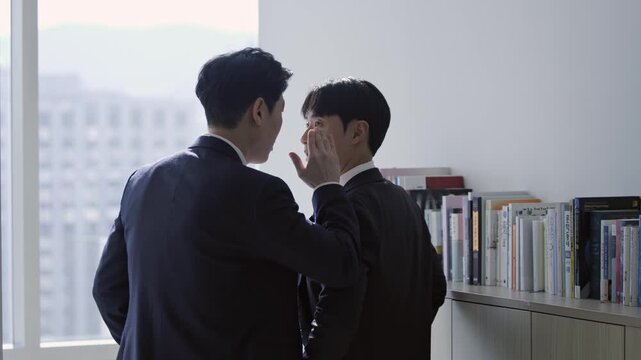 Two businessmen sharing a secret or confidential information, whispering in a modern office. Concepts of gossip, privacy, communication, and corporate intrigue.