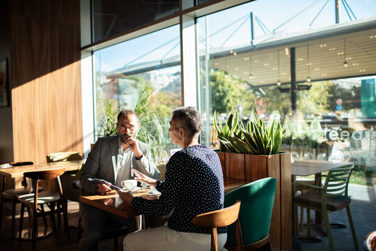 Business colleagues meeting over coffee in modern cafe