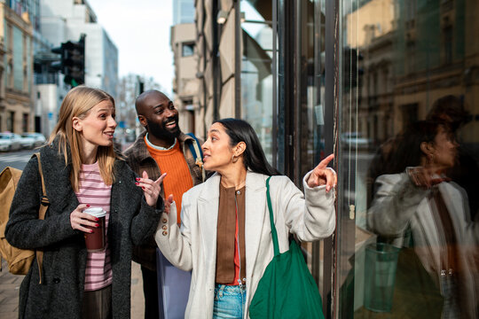 Three friends window shopping on urban city street