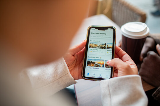 Traveler using smartphone travel app at coffee shop table