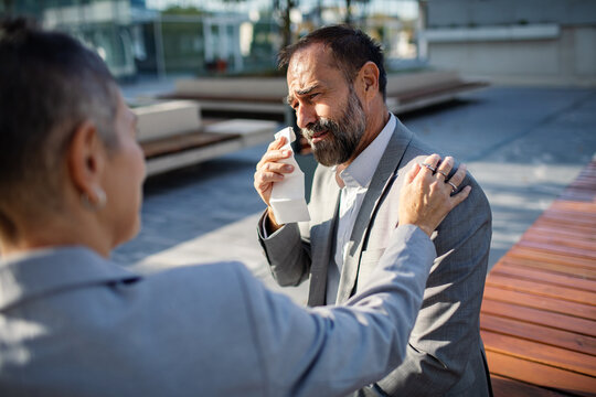 Coworker comforting distressed businessman outside office