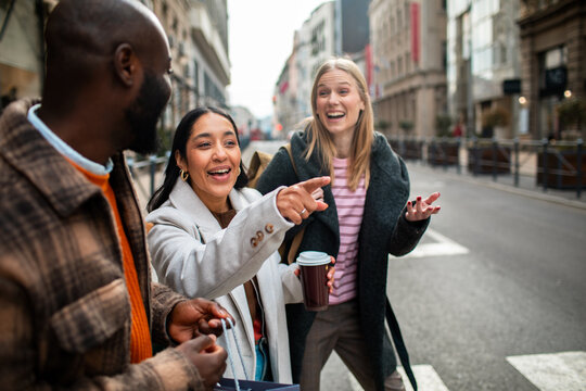 Friends laughing and pointing on city street