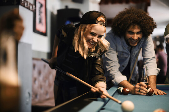 Friends playing billiards together at a bar