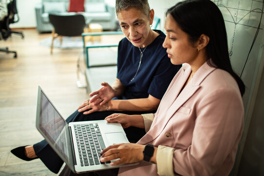 Two colleagues collaborating on laptop in modern office