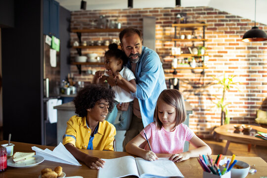 Father helping children with homework in kitchen