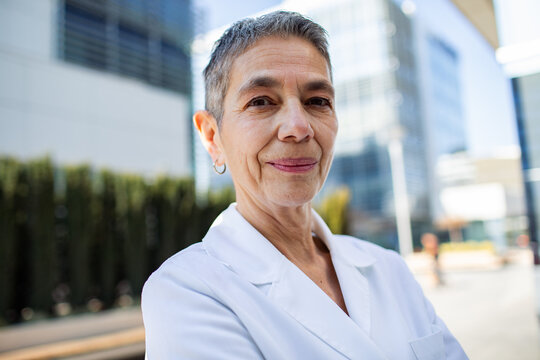 Confident senior female doctor outside modern hospital