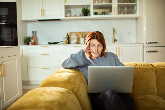 Woman using laptop on sofa in modern kitchen